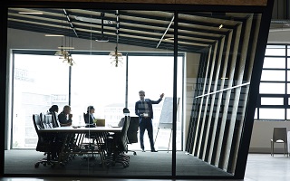 Male professor teaching inside a glass room